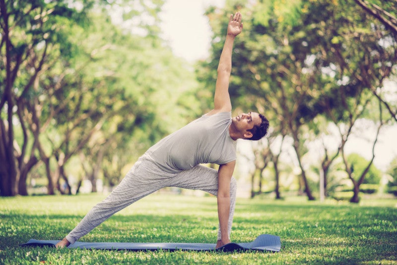 Inspired Indian man doing yoga asanas in city park