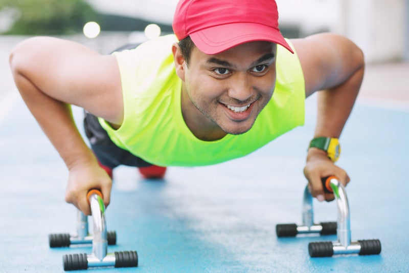 smiling man doing pushup at the gym
