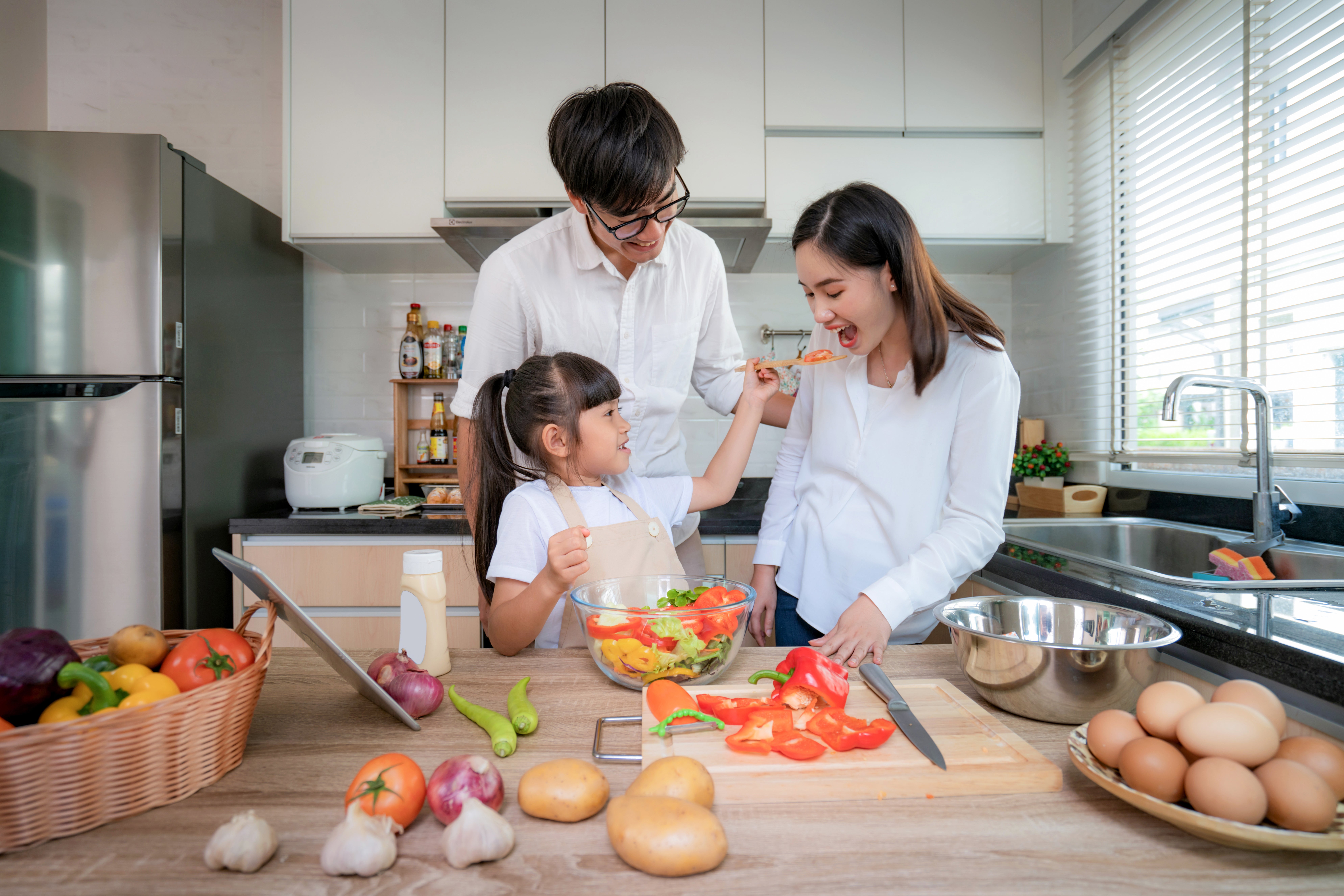 Asian daughters feeding salad to her mother and her father stand