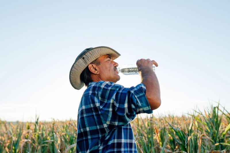 profile view of a senior farmer drinking bottled water.