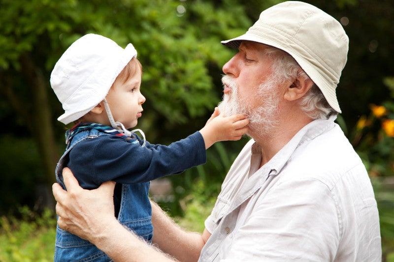 Grandchild grabbing grandfather's beard while having fun outdoors, knowing functional medicine has helped increase their neighborhood health and reduced pollutant exposures.