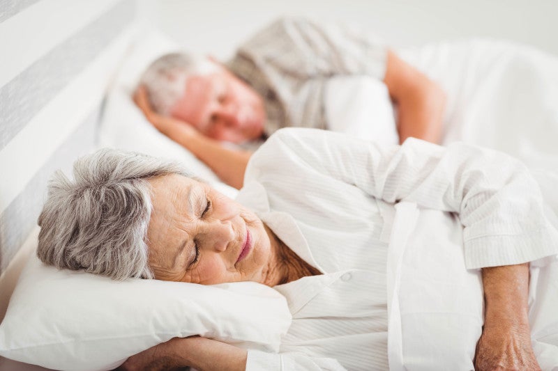 Senior couple sleeping on bed in bedroom refreshing their cardiovascular system, since sleep deprivation alters multiple aspects of behavior and physiology.