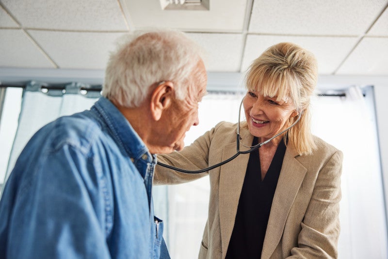 Physician performing an annual exam focusing on the functional medicine approach, to reduce social isolation and disease in her older patient.