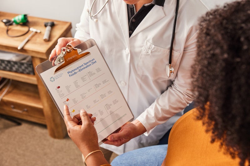 A closeup of a doctor showing her patient her clipboard full of functional medicine resources from the IFM's toolkit.