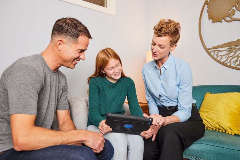 A doctor showing a little girl and her dad the functional medicine matrix on an ipad so they can better understand the patient's health conditions.