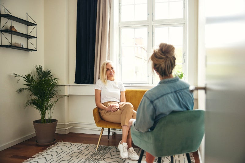 Smiling psychologist listening to a female client during a therapy session in her office